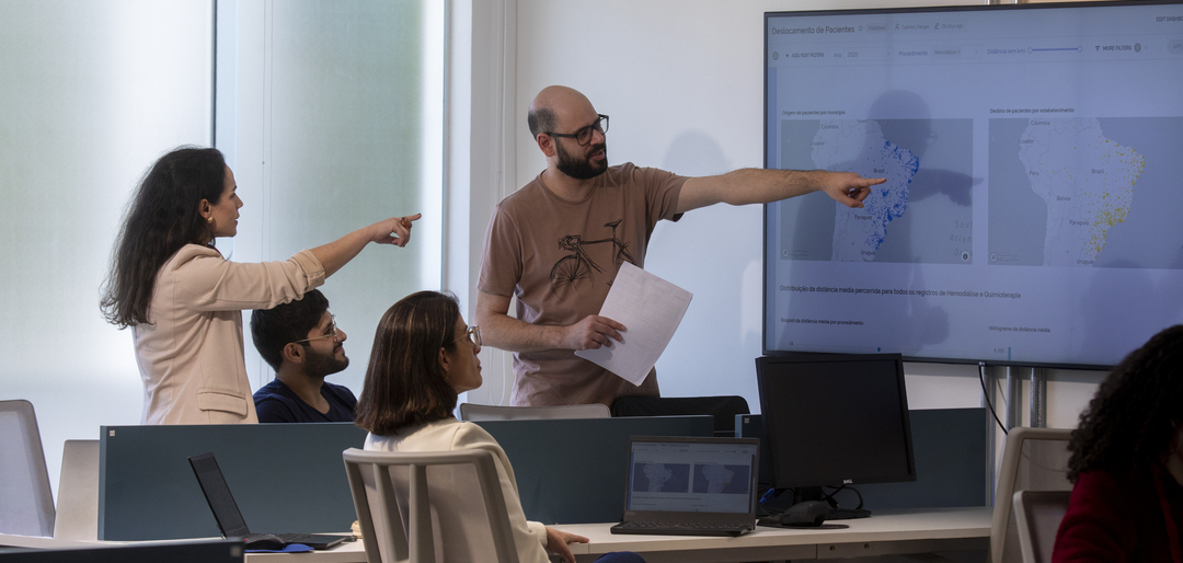 Equipe analisando dados de saúde dos colaboradores em tela com mapas e gráficos em ambiente corporativo